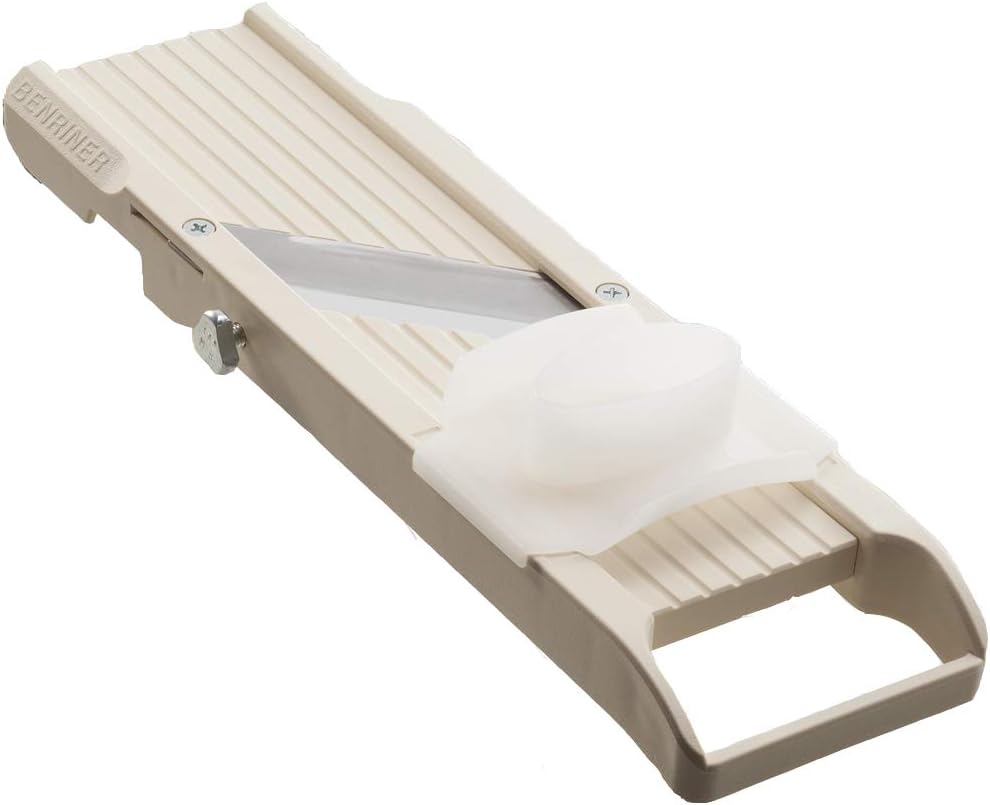 Ivory Benriner No. 64 Japanese mandoline slicer with its stainless blade set diagonally across the bed and a frosted finger guard resting on the ramp