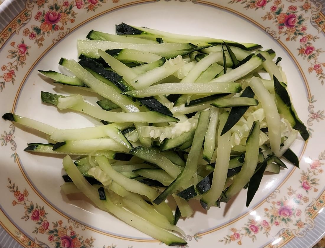 Plate of matchstick-cut cucumber with the skin left on, cut on a Benriner comb blade